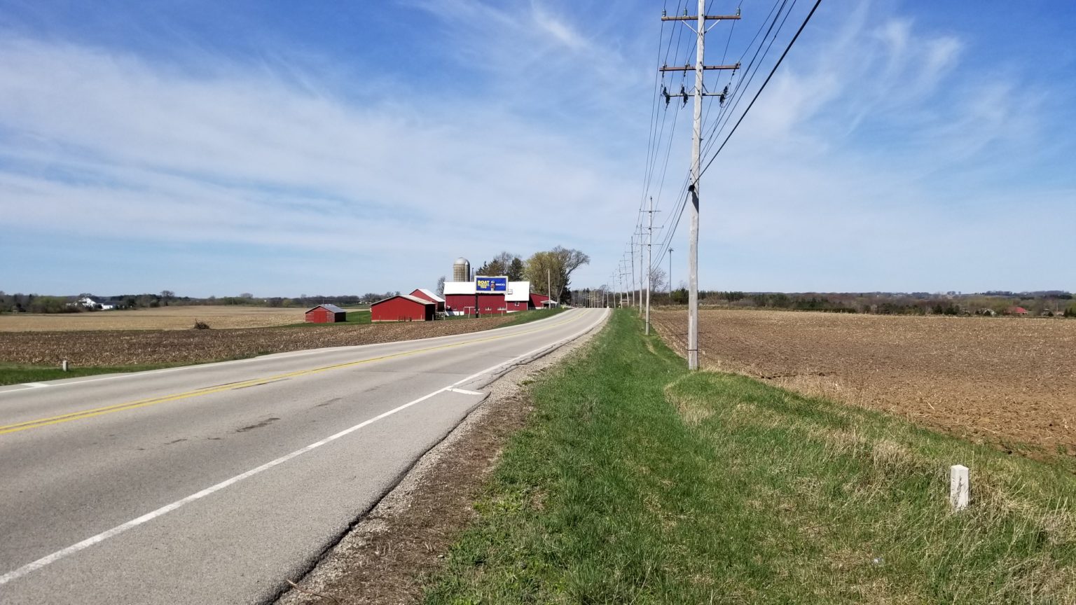 Rural road lined by farmland and utility poles