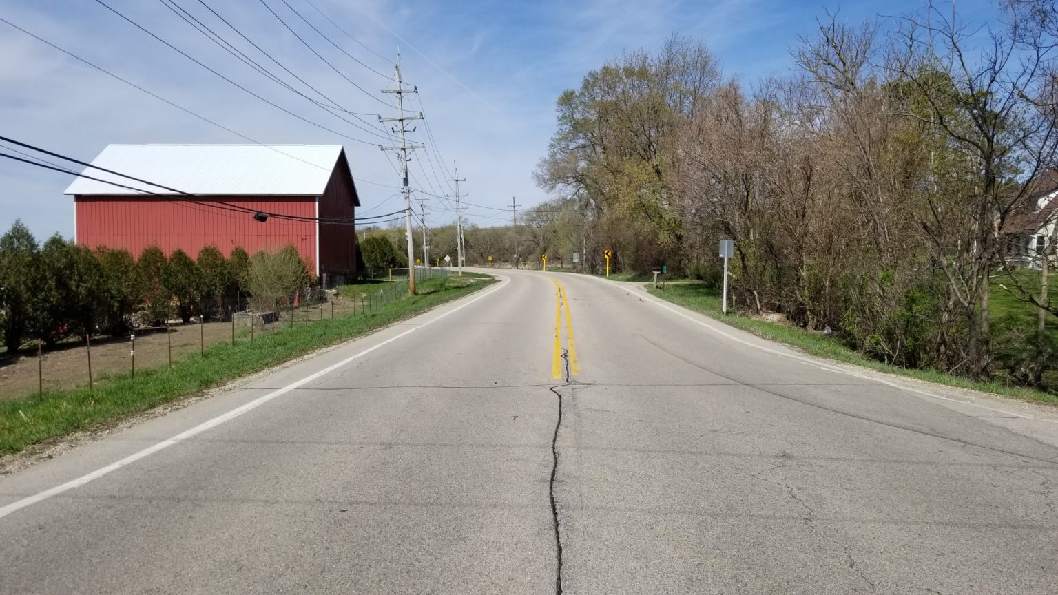 Curve in the road with farm building on the left