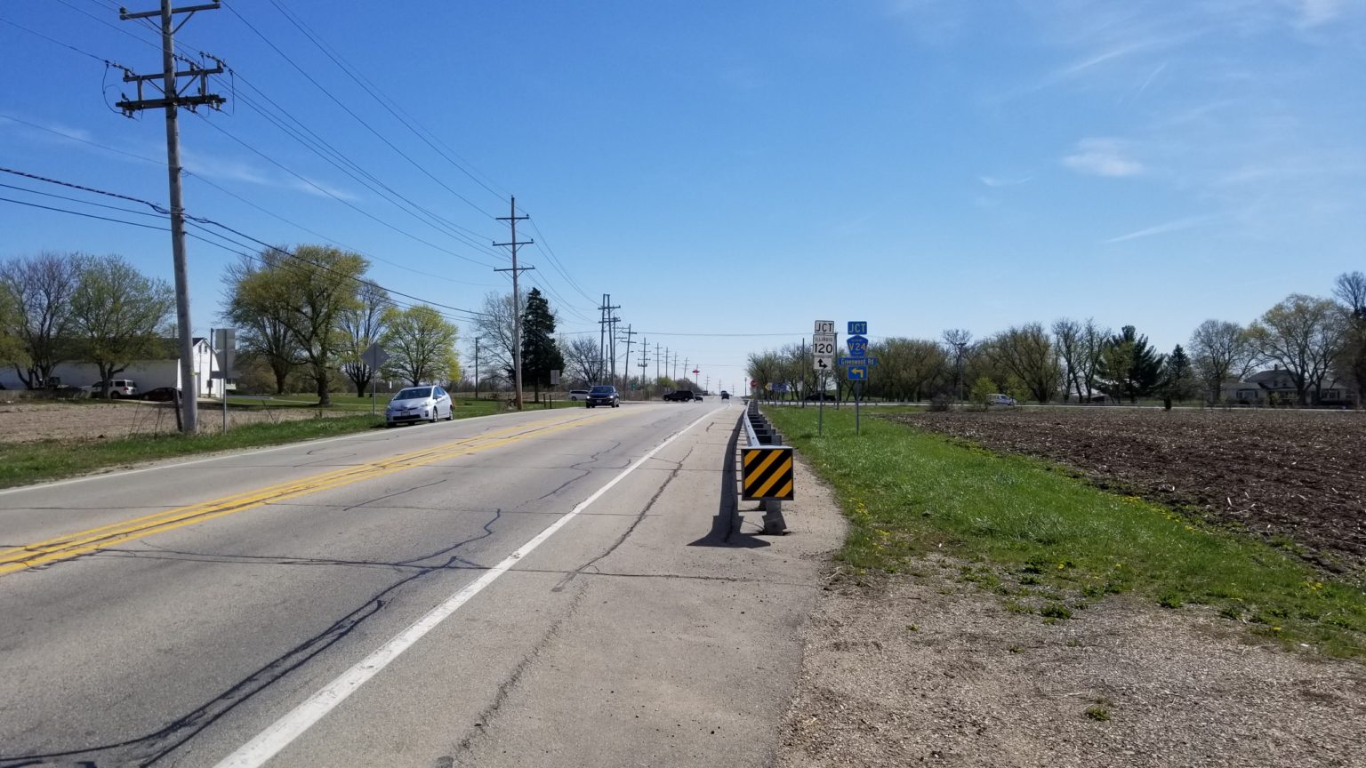 Road with farmland on the sides and a large barricade on the side